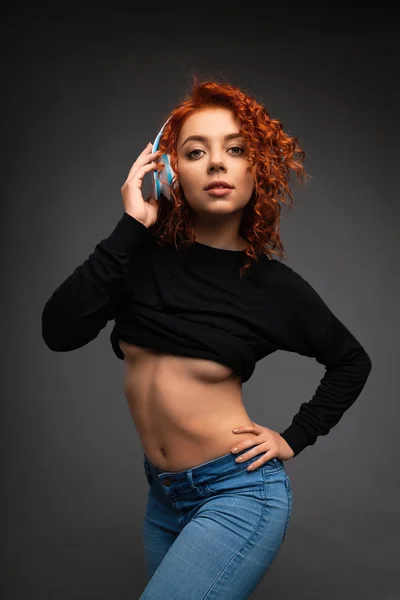 Curly red-haired dancing girl in headphones with a half-naked bo — Stock Photo, Image