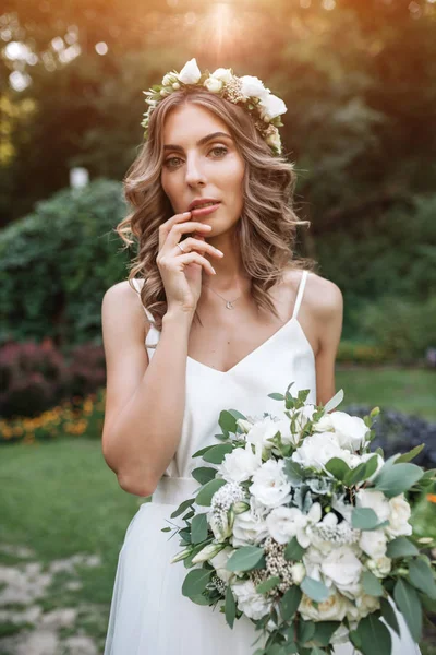 Lovely girl in wedding dress holding a bouquet of white flowers — Stock Photo, Image