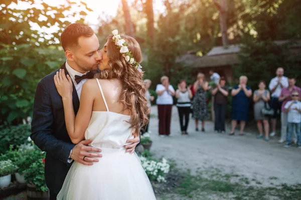 Der Bräutigam küsst die Braut vor den Gästen am Ausgang — Stockfoto
