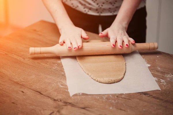 Руки катятся тесто для пряников на деревянный стол — стоковое фото