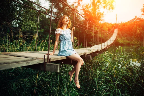 Jovem menina bonita de pé na ponte sobre o rio . — Fotografia de Stock