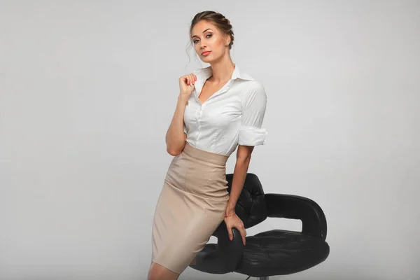 Bela mulher de negócios em uma camisa de escritório branco inclinado em um banco de bar de couro preto — Fotografia de Stock
