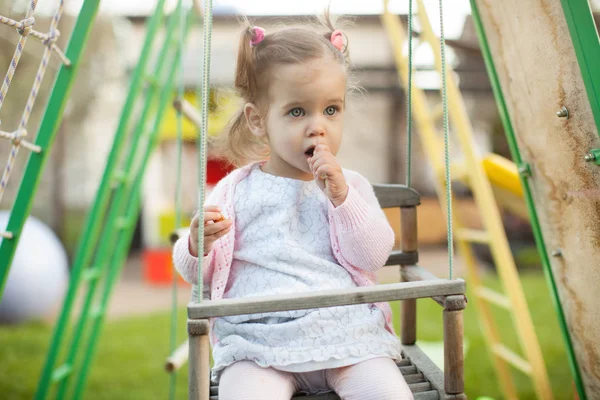 Grappige kleine kind, schattig peuter meisje in mooie jurk plezier op een schommel in het park op zomerdag — Stockfoto