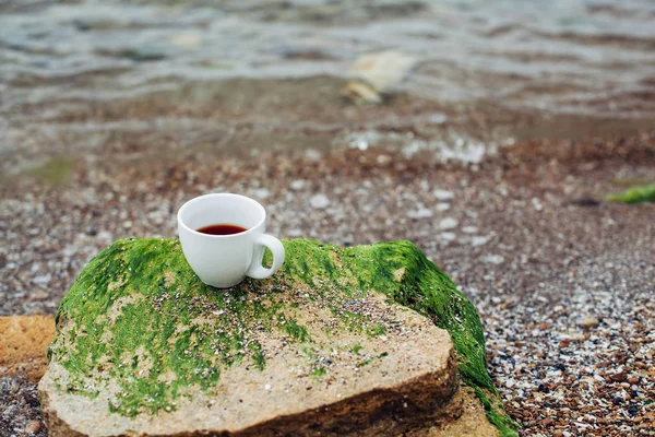 Xícara de café na água do mar e fundo de pedra. Frescura do mar conceito matutino — Fotografia de Stock