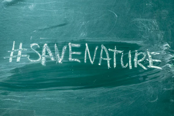Save the nature hashtag it handwritten with white chalk on a green blackboar