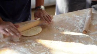 Baker Chef, restoran fırınının mutfağındaki mutfak masasında merdaneli taze hamur hazırlıyor..