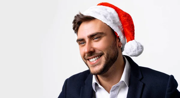 Junge hübsche kaukasische Kerl in Business-Anzug und Weihnachtsmann Hüte steht auf weißem Hintergrund im Studio und Zähne smilie — Stockfoto
