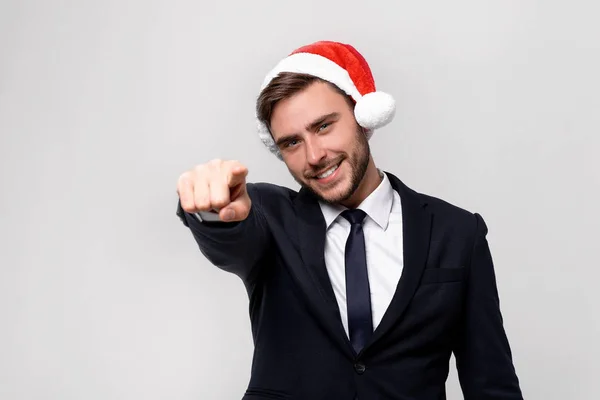 Jovem cara caucasiano bonito em terno de negócios e chapéus de Papai Noel fica no fundo branco em estúdio smilie e mostrando Dedo para a câmera . — Fotografia de Stock