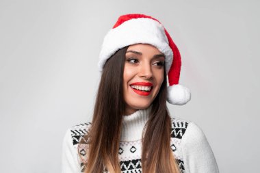 Beyaz stüdyo arka planında kırmızı Noel Baba şapkalı güzel beyaz kadın. Noel ve Yeni Yıl tatili konsepti.