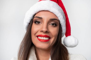Beyaz stüdyo arka planında kırmızı Noel Baba şapkalı güzel beyaz kadın. Noel ve Yeni Yıl tatili konsepti.