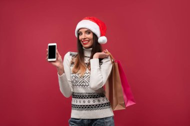 Kırmızı stüdyo arka planında kırmızı Noel Baba şapkalı güzel beyaz kadın. Noel ve Yeni Yıl tatili konsepti.