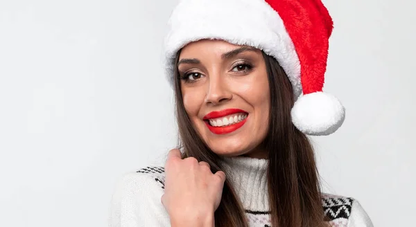 白いスタジオの背景に赤いサンタの帽子で美しい白人女性の肖像画を閉じます。クリスマスと年末年始のコンセプト. — ストック写真