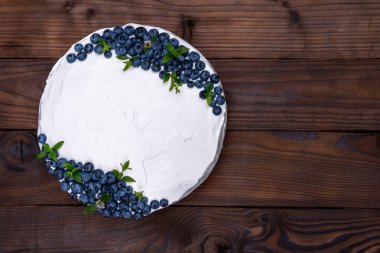 İştah açıcı cheesecake kek bisküvi yastığı süslemeli beyaz krema yaban mersini ve nane şekeri ahşap kırsal masa üzerinde duruyor. 
