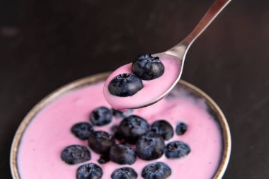 Siyah koyu masa arka planda duran seramik kase lezzetli taze yaban mersini yoğurt sallamak tatlı. 