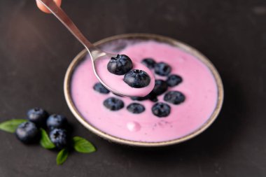 Siyah koyu masa arka planda duran seramik kase lezzetli taze yaban mersini yoğurt sallamak tatlı. 