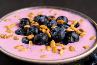 Siyah koyu masa arka planda duran seramik kase lezzetli taze yaban mersini yoğurt sallamak tatlı. 