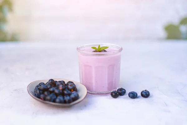 Sabroso yogur de arándano fresco agitar el postre en vidrio de pie sobre fondo de mesa blanca . — Foto de Stock