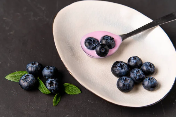 Ízletes friss áfonyás joghurt rázza desszert kerámia tál álló fekete sötét asztal háttér. — Stock Fotó