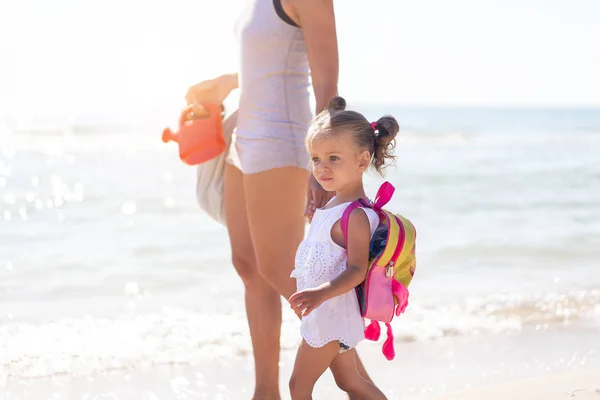 Young Caucasian mother with little daughter walk warm summer day along the sea coast. Summer family vacation concept. Friendship mom and child. — Stock Photo, Image