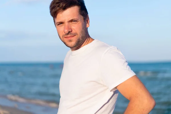 Kaukasier steht am Strand des Meeres und trägt weißes Hemd — Stockfoto