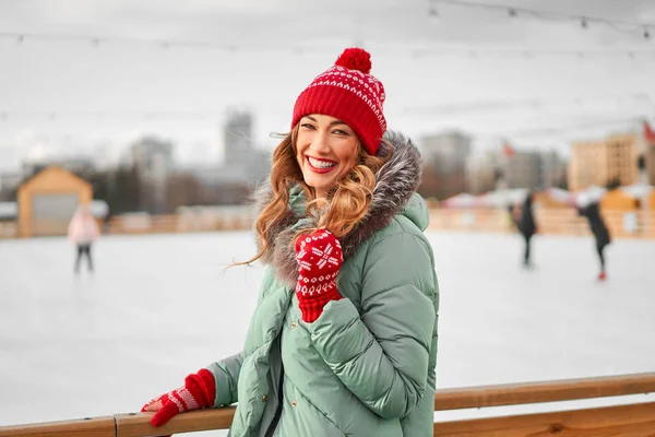 Beautiful lovely middle-aged girl with curly hair warm winter jackets stands ice rink background Town Square. — 스톡 사진