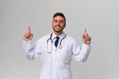 Beyaz tıbbi önlüklü yakışıklı modern doktor beyaz arka planda stüdyoda duruyor. Tıp fakültesinde öğrenci stajyeri..