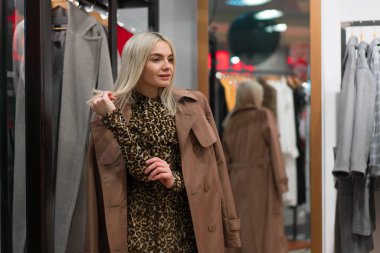 Moda butiğinde bir beyaz kadın sonbahar sezonu için kıyafet seçiyor..