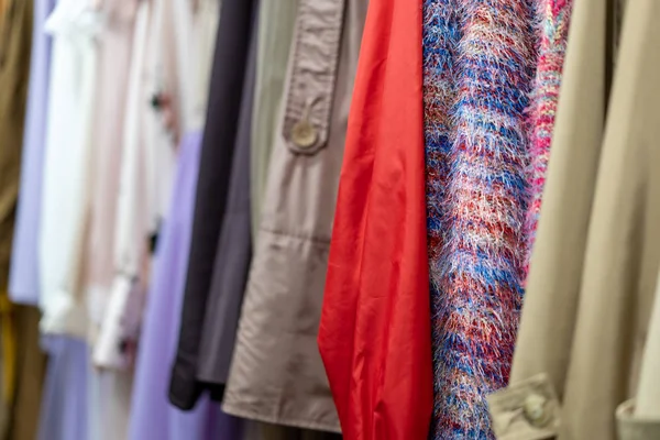 Multi colored clothing shirts hang on hangers in a shop background. A variety of clothes  hanging in the wardrobe.