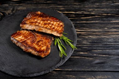 kızarmış et sulu parça siyah ahşap bir masaya karşı bir taş plaka üzerinde yatıyor