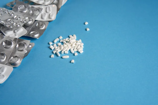 Blister vuoti usati da compresse colore argento e bianco e pillole si trovano su sfondo medico blu — Foto Stock