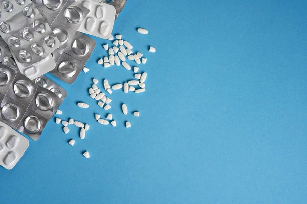 Blister vuoti usati da compresse colore argento e bianco e pillole si trovano su sfondo medico blu — Foto Stock