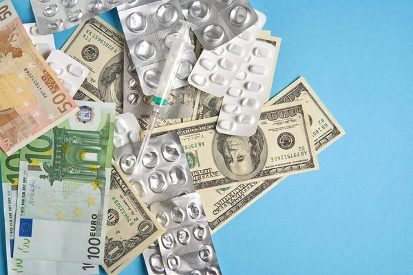 Таблетки пустые пузыри для наркотиков индивидуальный шприц и деньги лежат на синем фоне — стоковое фото