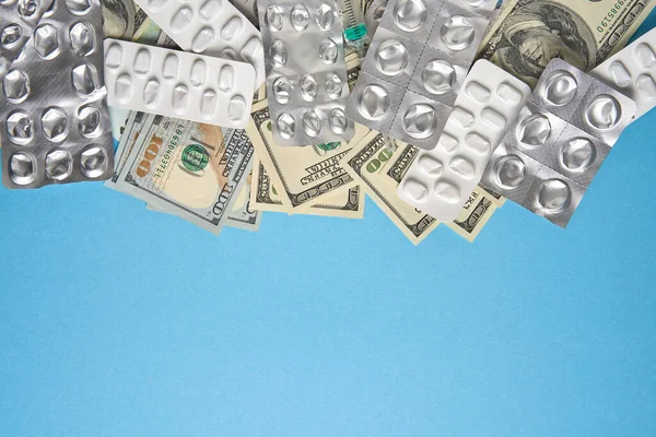 Таблетки порожні пухирі для наркотиків окремий шприц і гроші лежать на синьому фоні — стокове фото