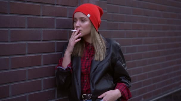 Ung Vacker snygg europeisk flicka står på bakgården nära att bygga och röka en cigarett. Stress. Dålig vana, ohälsosam livsstil. — Stockvideo