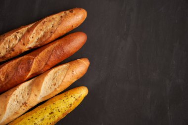 Three crispy french baguettes lie on an old wooden table with free space for text