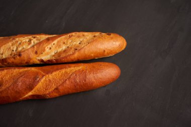 Two crispy french baguettes lie on an old wooden table with free space for text