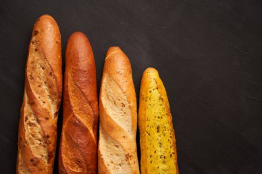 Three crispy french baguettes lie on an old wooden table with free space for text
