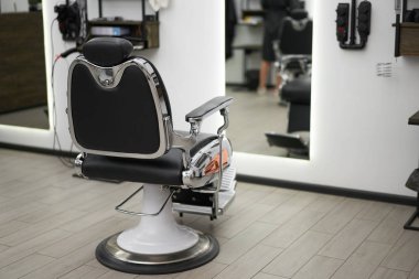 Classic vintage barber chair stands opposite mirror stylish white barber shop interior. 