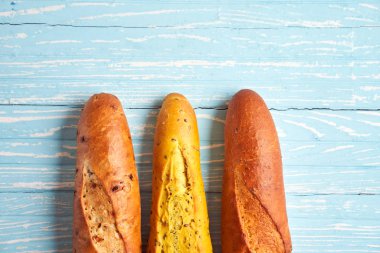 Three crispy french baguettes lie on an old wooden table with free space for text