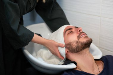 Woman applying shampoo massaging hair customer  Man wash hair in beauty salon Hairdresser washing hair. Happy caucasian guy enjoy service in barbershop 