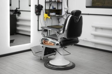 Classic vintage barber chair stands opposite mirror stylish white barber shop interior. 