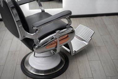 Classic vintage barber chair stands opposite mirror stylish white barber shop interior. 