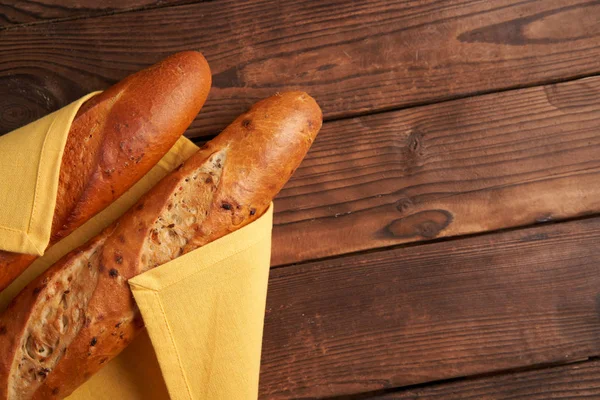 Two crispy french baguettes lie on an old wooden table with free space for text — Stok fotoğraf