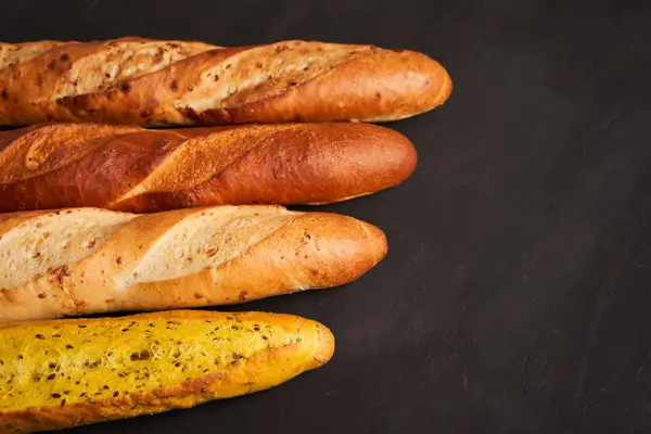 Três baguetes francesas crocantes jazem em uma mesa de madeira velha com espaço livre para texto — Fotografia de Stock