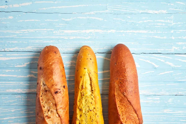 Três baguetes francesas crocantes jazem em uma mesa de madeira velha com espaço livre para texto — Fotografia de Stock