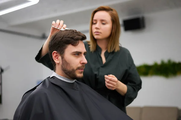 Красивий блакитноокий чоловік сидить у перукарні. Перукарня для стрижки волосся. Жіночий перукар . — стокове фото