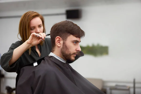 Красивий блакитноокий чоловік сидить у перукарні. Перукарня для стрижки волосся. Жіночий перукар . — стокове фото