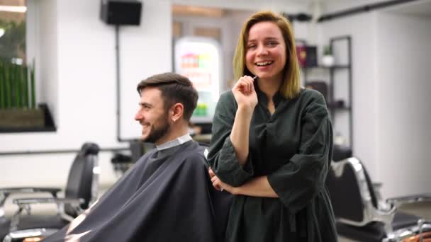 Komea sinisilmäinen mies parturissa. Kampaaja kampaaja nainen leikkaa hiuksensa. Naisparturi. — kuvapankkivideo