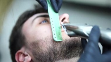 Genç, güzel beyaz kadın kuaför modern berber dükkanında sakal kesiyor yakışıklı adam.