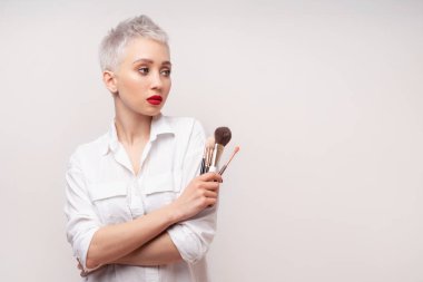 Portre makyözünü kapat. Kursları hazırla. Kişisel görünüm ana sınıflandırması kavramı. Moda uzmanı. Kadın elinde makyaj fırçası tutuyor. Beyaz arkaplanda stüdyo çekimi